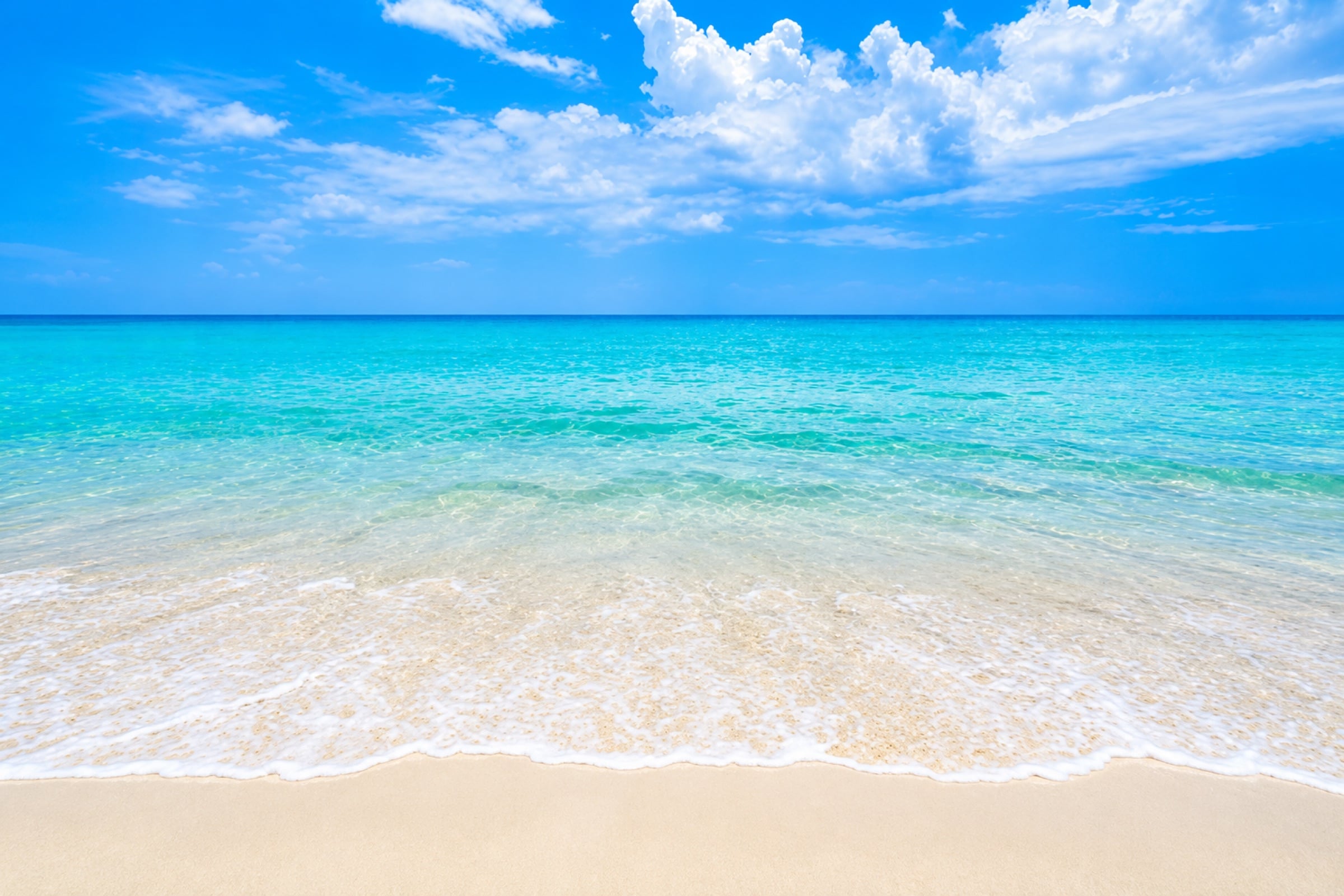 Clear turquoise water under a bright blue sky with white clouds