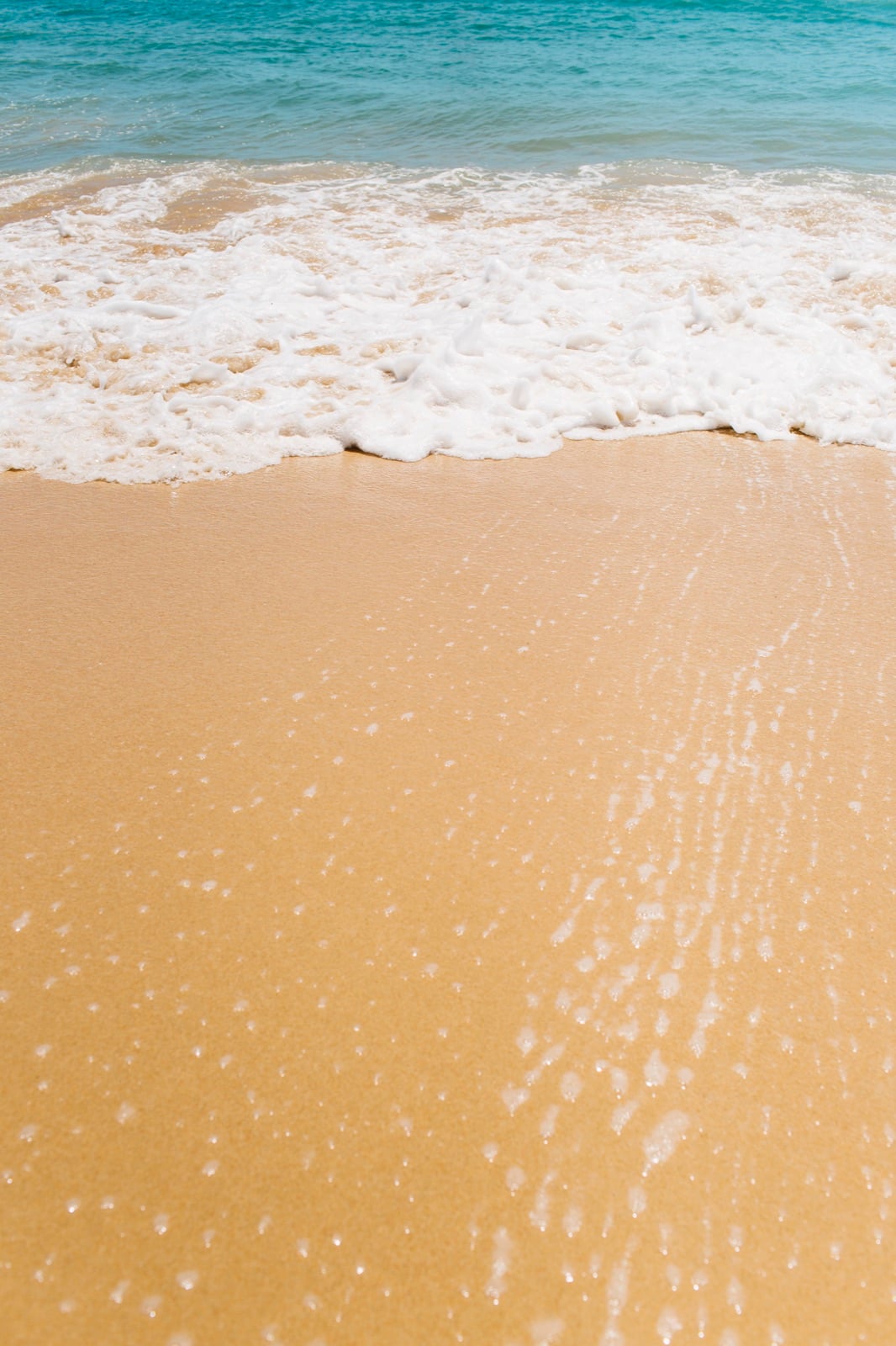 Foamy surf sliding over smooth golden sand